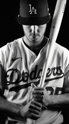 a black and white photo of a baseball player holding a bat with his hands on his hips