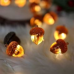 several lit candles sitting on top of a white fur covered table next to pine cones