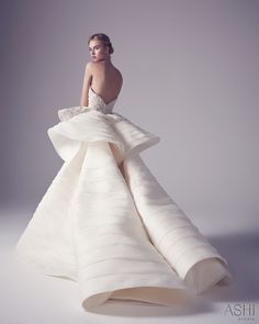 a woman in a white dress is standing with her back turned to the camera and she's wearing a high - low gown