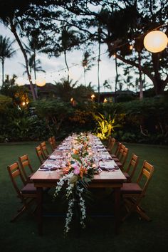 a long table set up with flowers and candles for an outdoor dinner party in the evening