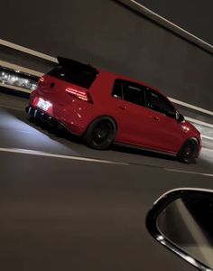 a red car driving down a street at night