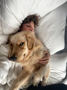 a woman laying in bed with her dog