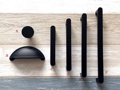 black handles and knobs are arranged on a wood paneled surface with measurements for each one