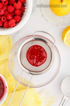 raspberry sauce in a strainer next to lemons and strawberries