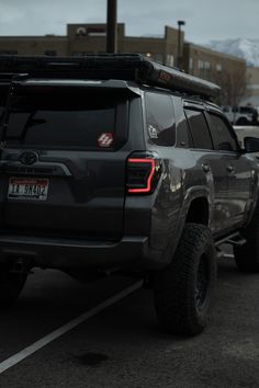 the back end of a gray truck parked in a parking lot next to other cars