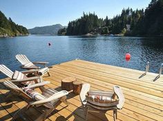 two lawn chairs sitting on top of a wooden dock