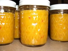 four jars filled with yellow liquid sitting on top of a counter