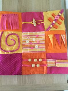 a close up of a piece of cloth on a wooden table with buttons and pins