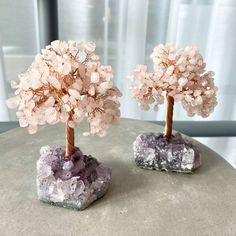 two small trees made out of rocks sitting on top of a stone table next to each other