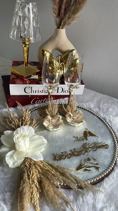 a table topped with two vases filled with flowers next to a book and lamp