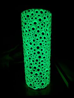 a lit up green vase sitting on top of a black table next to a knife