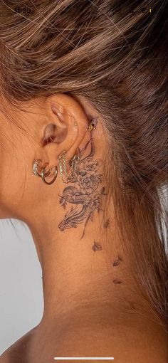 the back of a woman's neck has a tattoo on her left side ear