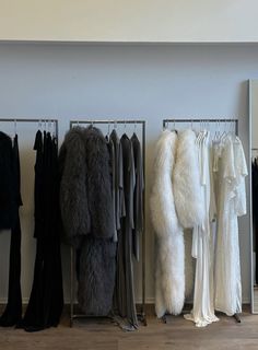 there are many coats and dresses hanging on the rack next to each other in this room