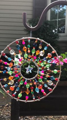 a colorful wind chime hanging from a metal pole in front of a house on a sunny day