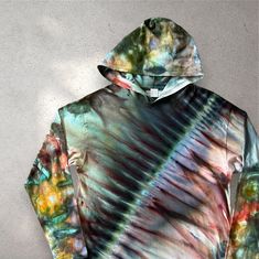 a tie dyed hoodie is hanging on a wall