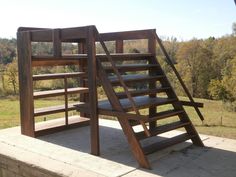 a set of wooden stairs sitting on top of a cement wall next to a field