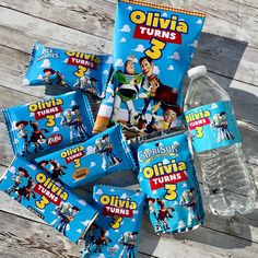 various children's snacks and water are laid out on a wooden table with the names olivia turns 3