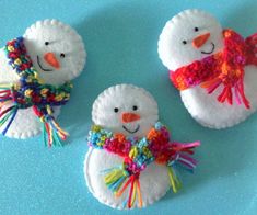 three snowmen made out of felt on a blue surface