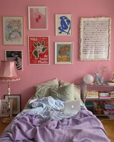 a bedroom with pink walls and lots of pictures on the wall above the headboard