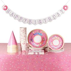 a pink table topped with donuts and sprinkles