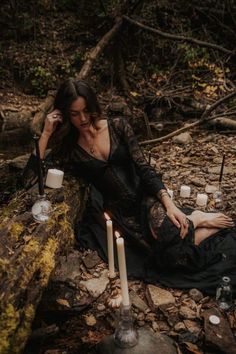 a woman is sitting on the ground with candles in front of her and looking down