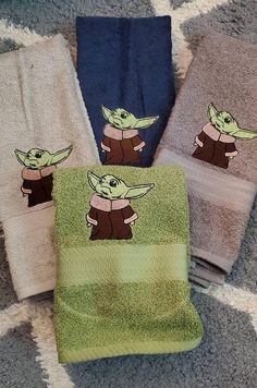 three towels with the image of baby yoda on them, one is green and two are blue