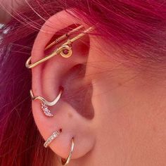 a woman with pink hair wearing three different ear piercings