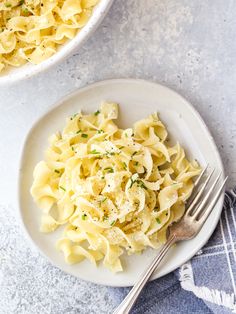 two plates filled with pasta on top of a blue and white table cloth next to silverware