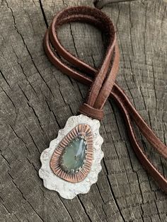 "This unique mixed metals pendant is entirely crafted by hand with primitive metalworking techniques. It features a very high quality aqua chalcedony gemstone with a copper & Sterling silver setting. The copper really makes the gemstone stand out in this piece. This pendant has lots of rustic charm, texture & patina. It is stamped with the Bible verse \"Nahum 1:17\". This would make the perfect inspirational gift for any occasion or as a reminder for oneself to always seek strength throu Artisan Hand-tooled Necklace For Gift, Artisan Necklace With Adjustable Patina, Artisan Teardrop Pendant Necklace, Silver Artisan Necklace With Patina, Artisan Silver Necklace With Patina, Artisan Teardrop Copper Necklace, Bohemian Hand Tooled Green Jewelry, Artisan Chrysoprase Necklaces For Jewelry Making, Artisan Teardrop Jewelry With Patina