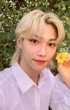 a woman with blonde hair holding a yellow flower