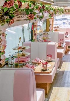 the inside of a restaurant with pink and white booths, flowers on the ceiling, and plates in front of them