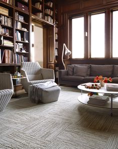 a living room filled with furniture and bookshelves next to a large book shelf