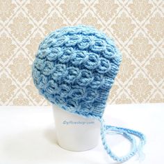 a crocheted blue hat is sitting on a white cup