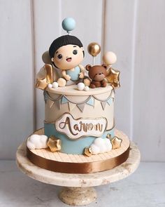 there is a cake that has a baby on it and gold balloons in the air