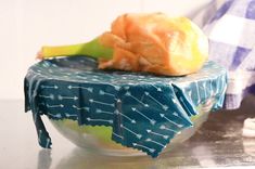 a plastic banana sitting on top of a glass bowl filled with something orange and blue