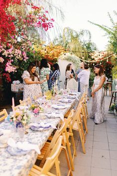 a group of people standing around a long table with plates and glasses on top of it