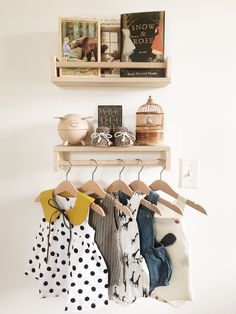 some clothes are hanging on a rack in front of a wall with books and pictures