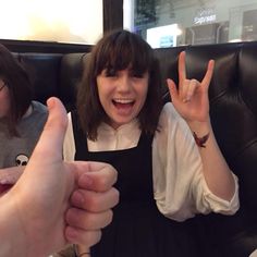 a woman sitting on top of a black couch holding up two fingers