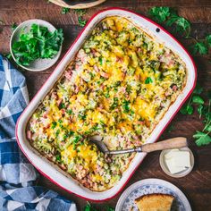 a casserole dish with meat and vegetables in it on a table next to bread