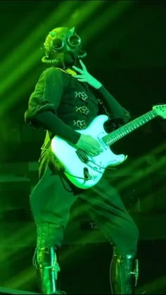 a man with green hair is playing an electric guitar