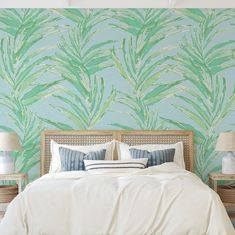 a large bed sitting under a green leaf wallpaper