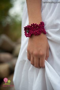 a close up of a person wearing a white dress with a red bracelet on their wrist