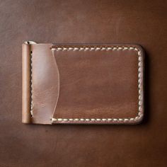 A Slim Leather Wallet that's Built for Cash and Cards. This wallet securely holds bills and cards while maintaining a slim profile, perfect for front-pocket carry. Quickly flip through your cash without having to remove your entire stack of bills. The solid brass spring bar clip ensures your money is secure and stays in your pocket.Our full-grain Horween leather means your wallet will develop character and patina. We hand-sew this wallet with thick Tiger Thread so it will never unravel or come a Handmade Classic Wallet, Artisan Hand-stitched Wallets, Artisan Hand-stitched Wallets For Everyday Use, Classic Hand-stitched Wallets As Gifts, Handmade Classic Trifold Wallets, Handmade Classic Leather Wallet, Classic Handmade Brown Trifold Wallet, Classic Handmade Leather Wallet, Classic Handmade Trifold Wallet For Everyday