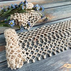 two pieces of crocheted fabric sitting on top of a wooden table next to flowers