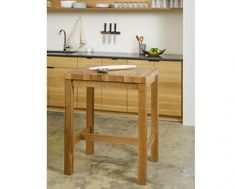 a wooden table sitting in the middle of a kitchen next to a counter top with knives on it