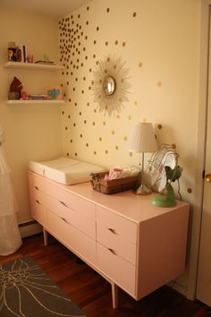 a baby's room with pink dresser and gold polka dot wallpaper