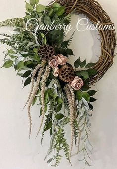 a wreath with flowers and greenery hanging on the wall