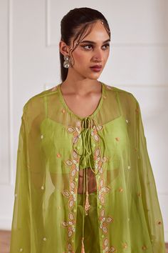 Green sheer cape with cutdana embellished floral motifs. Comes with crop top and sharara.
Components: 3
Pattern: Embroidered
Type Of Work: Cutdana,Sequin,Pearl
Neckline: Cape: Tie-up, Crop top: U-neck
Sleeve Type: Cape: Cape sleeves, Crop top: Sleeveless
Fabric: Semi Raw Silk, Georgette, Viscose Organza, Lining: Shantoon
Color: Green
Other Details: 
Attached lining
Closure:
Cape: Front drawstring
Crop Top: Back hook
Sharara: Side zip
Occasion: Cocktail,Sangeet - Aza Fashions Cape Sharara, Sheer Cape, Cape Sleeves, Sharara Set, Cape Dress, Fashion App, Top Sleeveless, Floral Motifs, Embroidered Silk