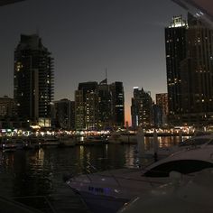 the city skyline is lit up at night, with boats in the water and lights on