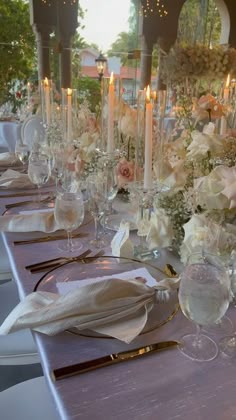 a long table is set with white flowers and candles for an elegant dinner or reception